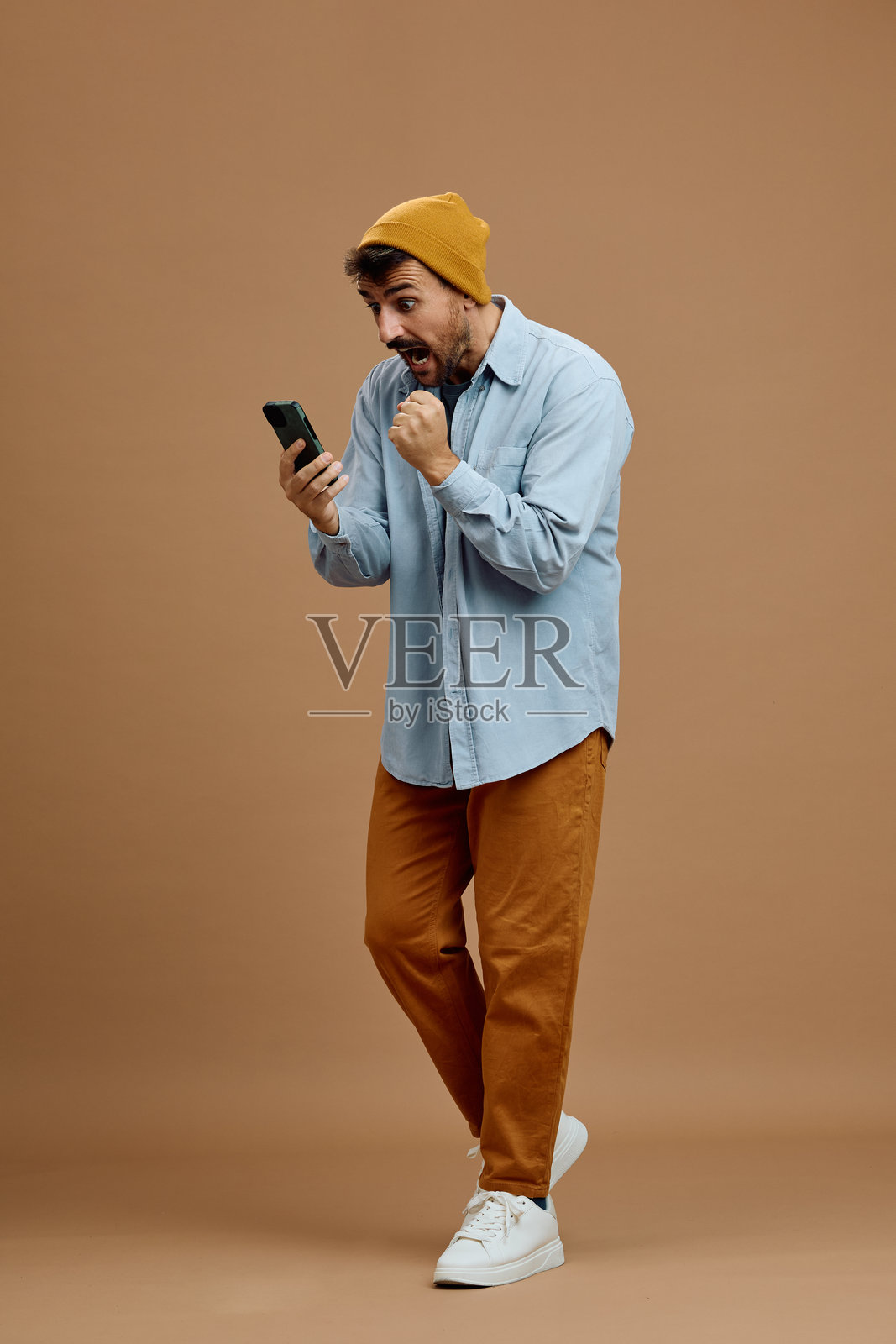 兴奋的男人在手机上阅读好消息时欢呼。照片摄影图片