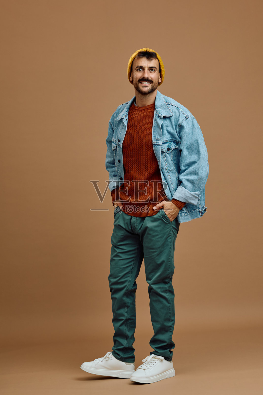 开心的男人双手插在口袋里看着镜头。照片摄影图片