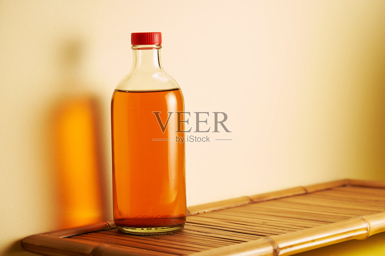 苹果醋瓶子置于黄色背景上照片摄影图片