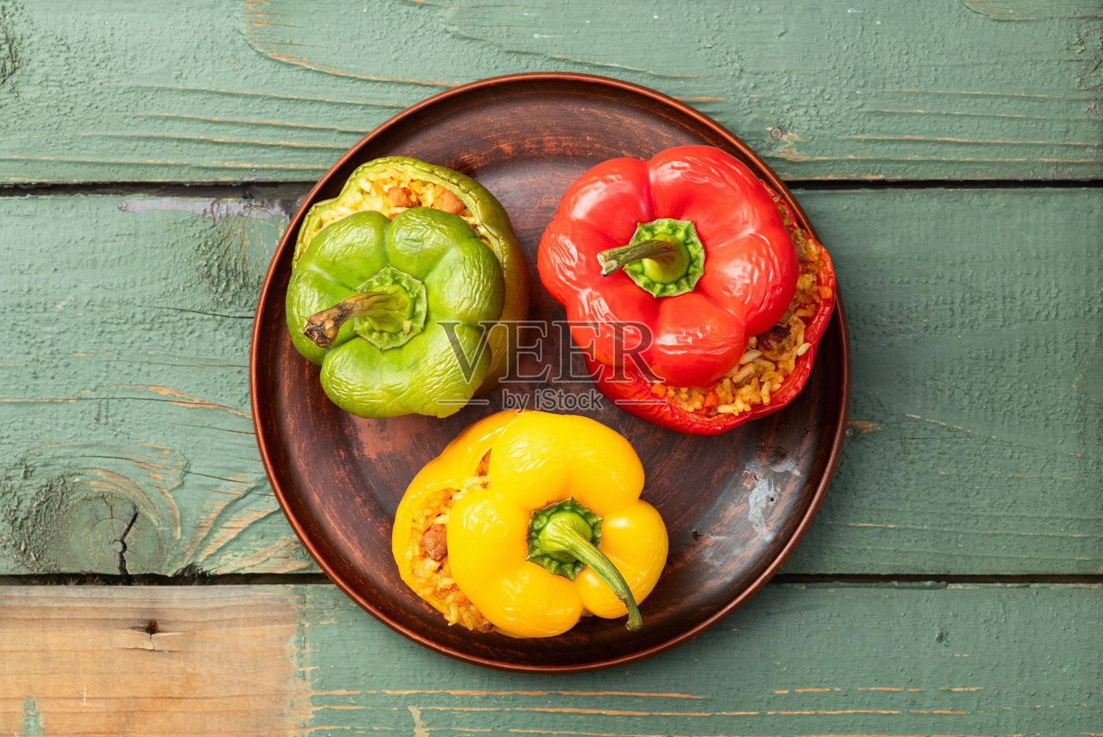 米饭、胡萝卜和肉馅的烤填充椒（红椒）。顶部视角，背景为乡村风格。照片摄影图片