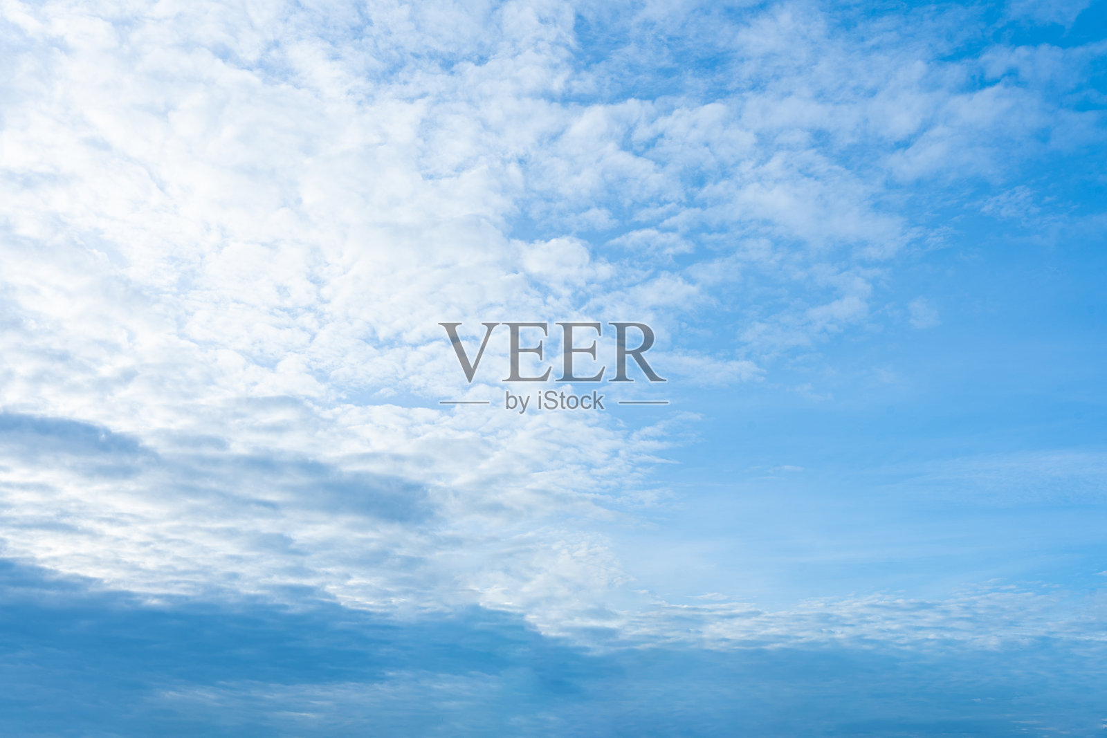 蓬松的白云在晴朗的蓝天上飘荡，描绘出一个美丽的夏日。照片摄影图片