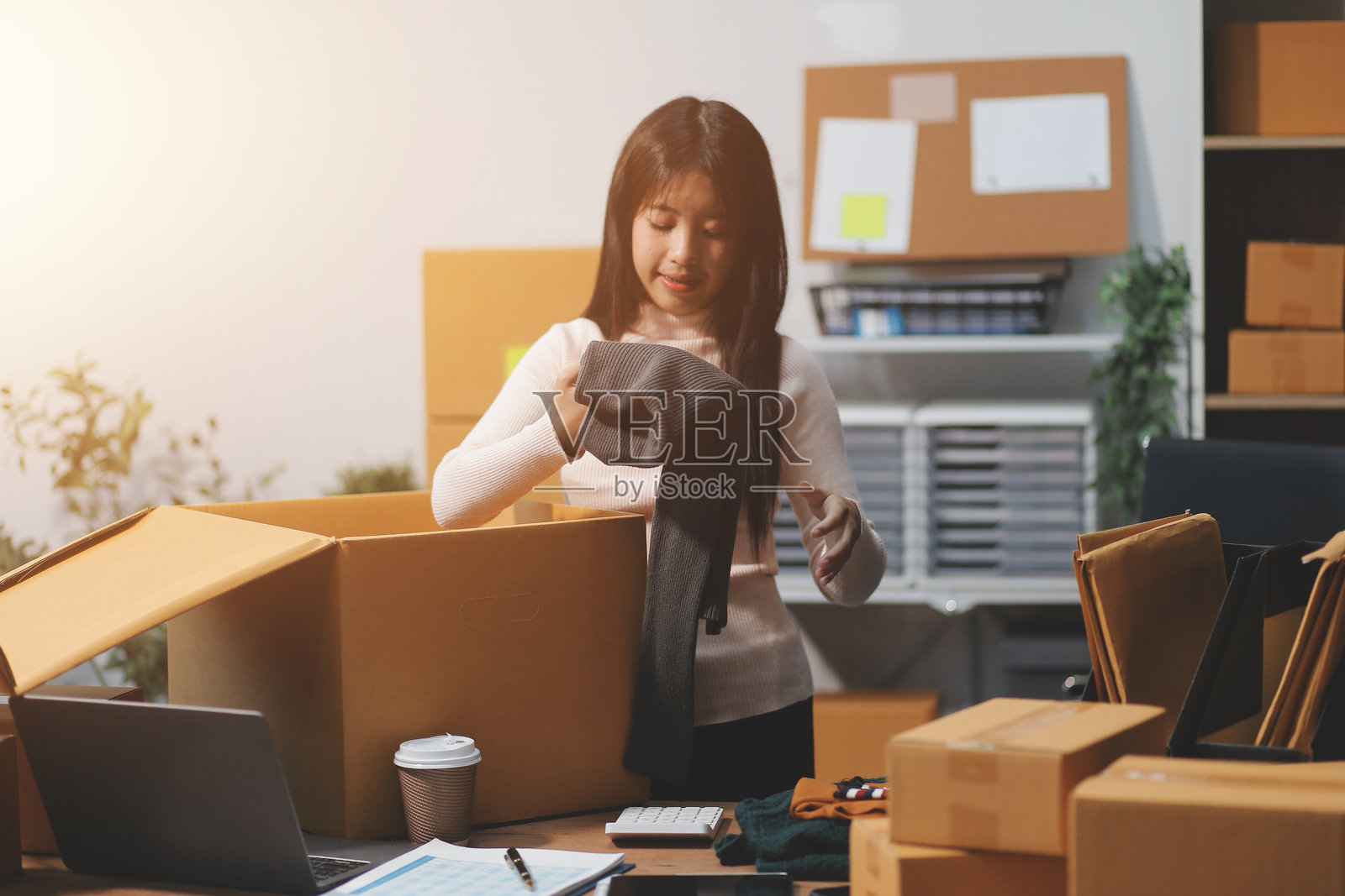 身穿围裙的亚洲女性创业者，使用笔记本电脑和箱子在线接收和审核订单，准备打包出售给客户，在线中小企业商业创意。照片摄影图片