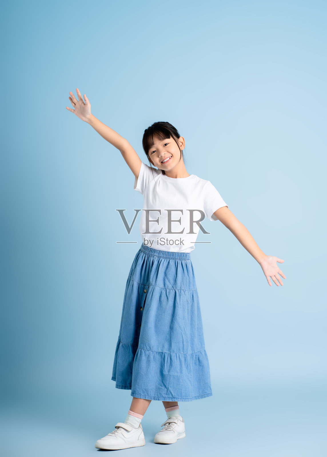 全身像的亚洲女孩在蓝色背景上摆姿势照片摄影图片