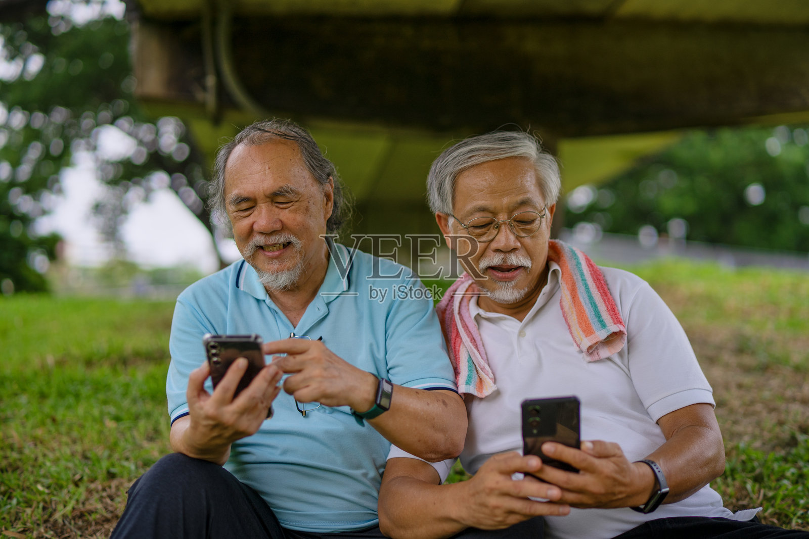 一群老年人在公园里锻炼和玩智能手机。照片摄影图片