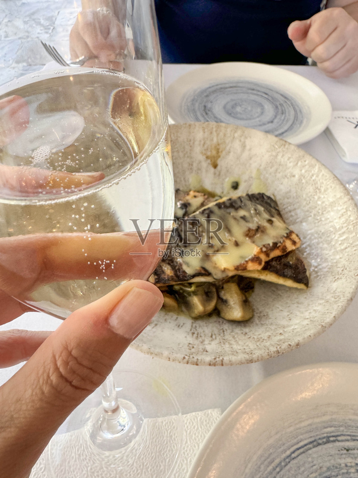 手握香槟酒杯，置于海鲜餐桌上。照片摄影图片