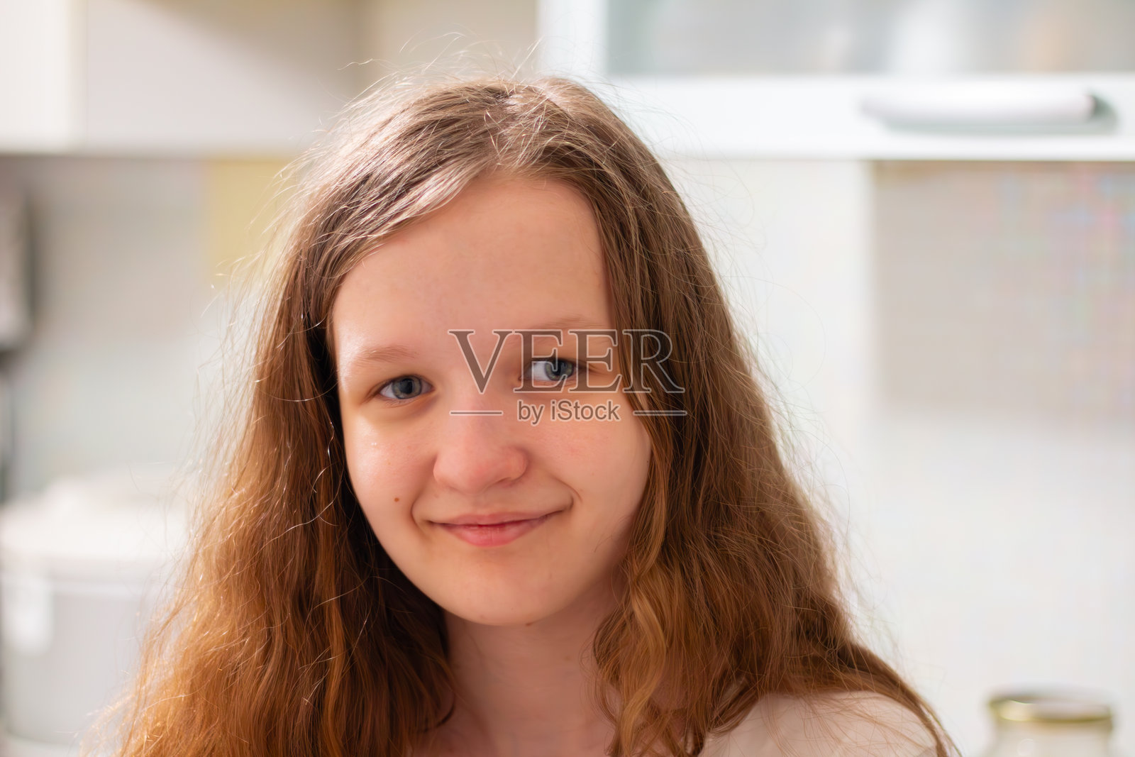 一个年轻女孩在明亮的厨房环境中温暖地微笑，散发出愉快的氛围。照片摄影图片