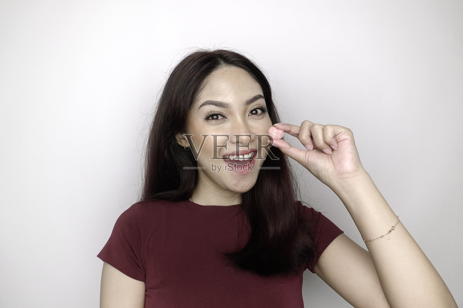 一位年轻的亚洲女性手持并注视着果冻糖。照片摄影图片