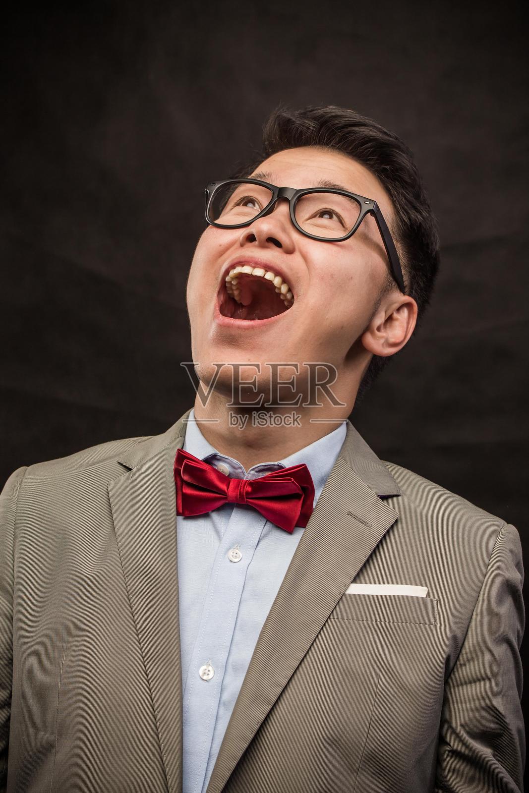 一位年轻的亚洲男子，戴着眼镜和蝴蝶结领带的肖像照片摄影图片