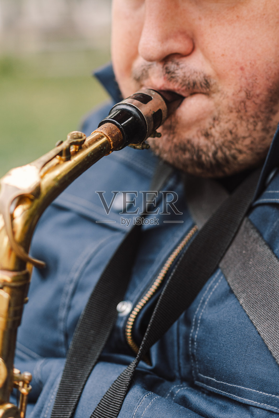 一位萨克斯演奏家在秋天的宁静公园里坐在长椅上演奏。照片摄影图片