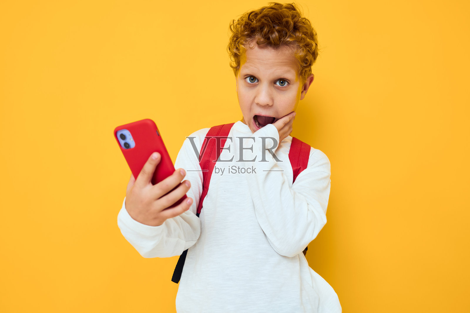 搞笑的男青少年使用手机教育孩子，生活方式，黄色背景照片摄影图片