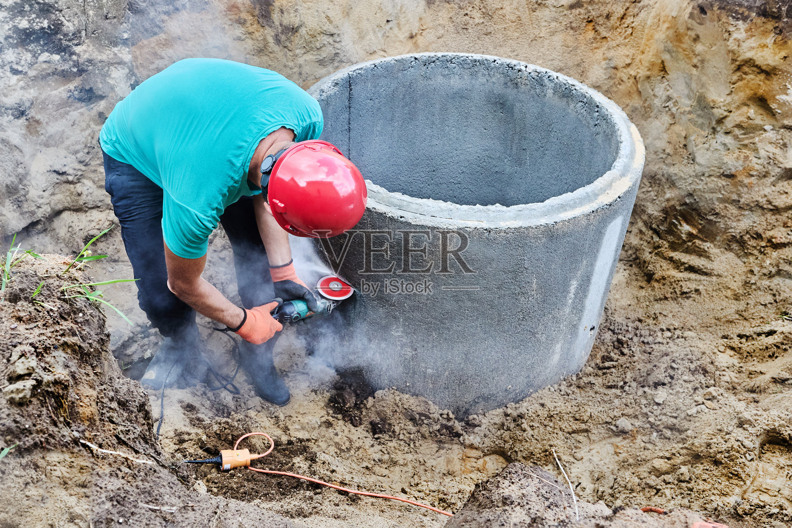 用于安装化粪池的角磨机配备金刚石切割片。照片摄影图片