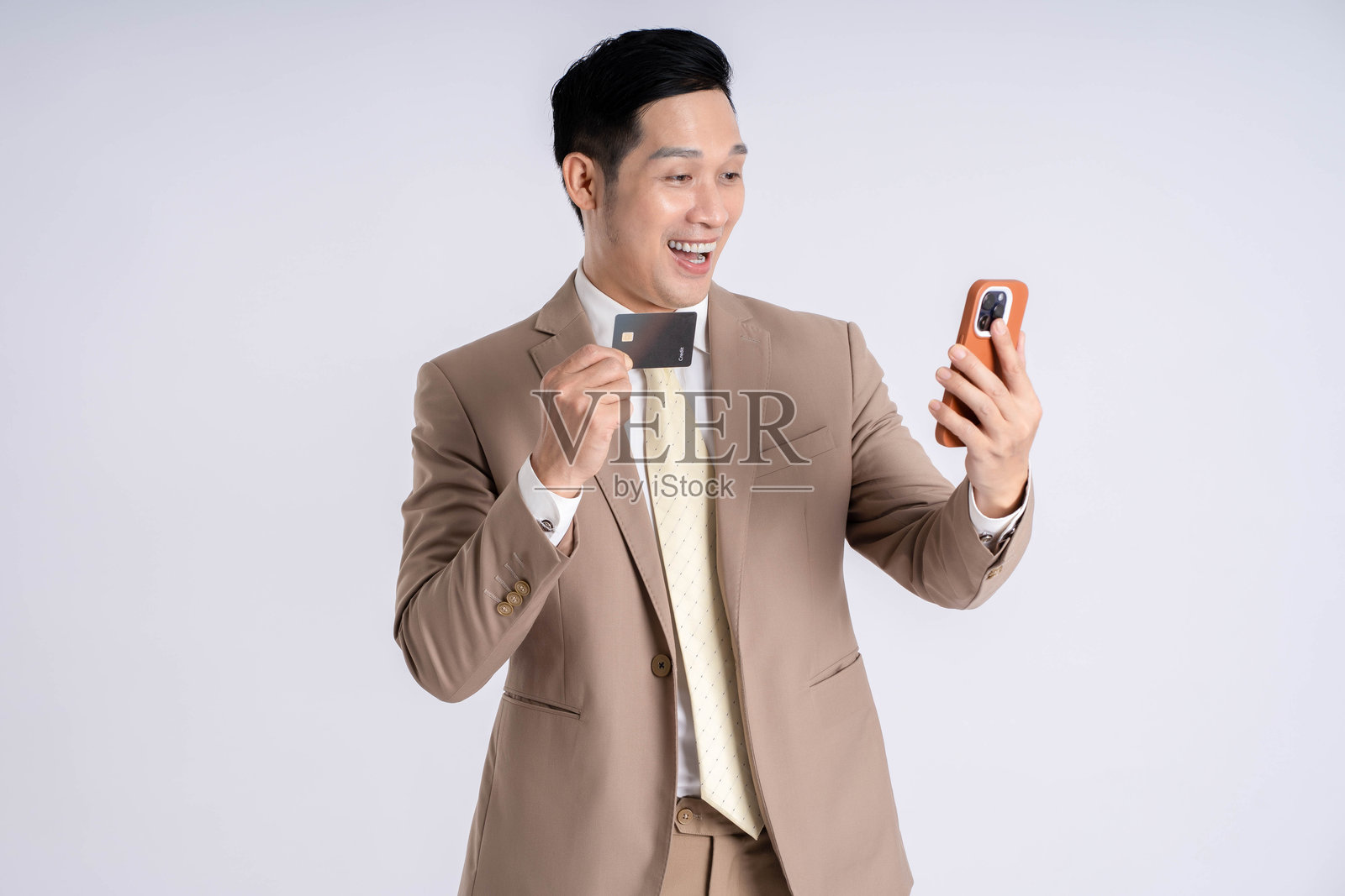 亚洲男性商人在白色背景下使用手机并持有信用卡照片摄影图片