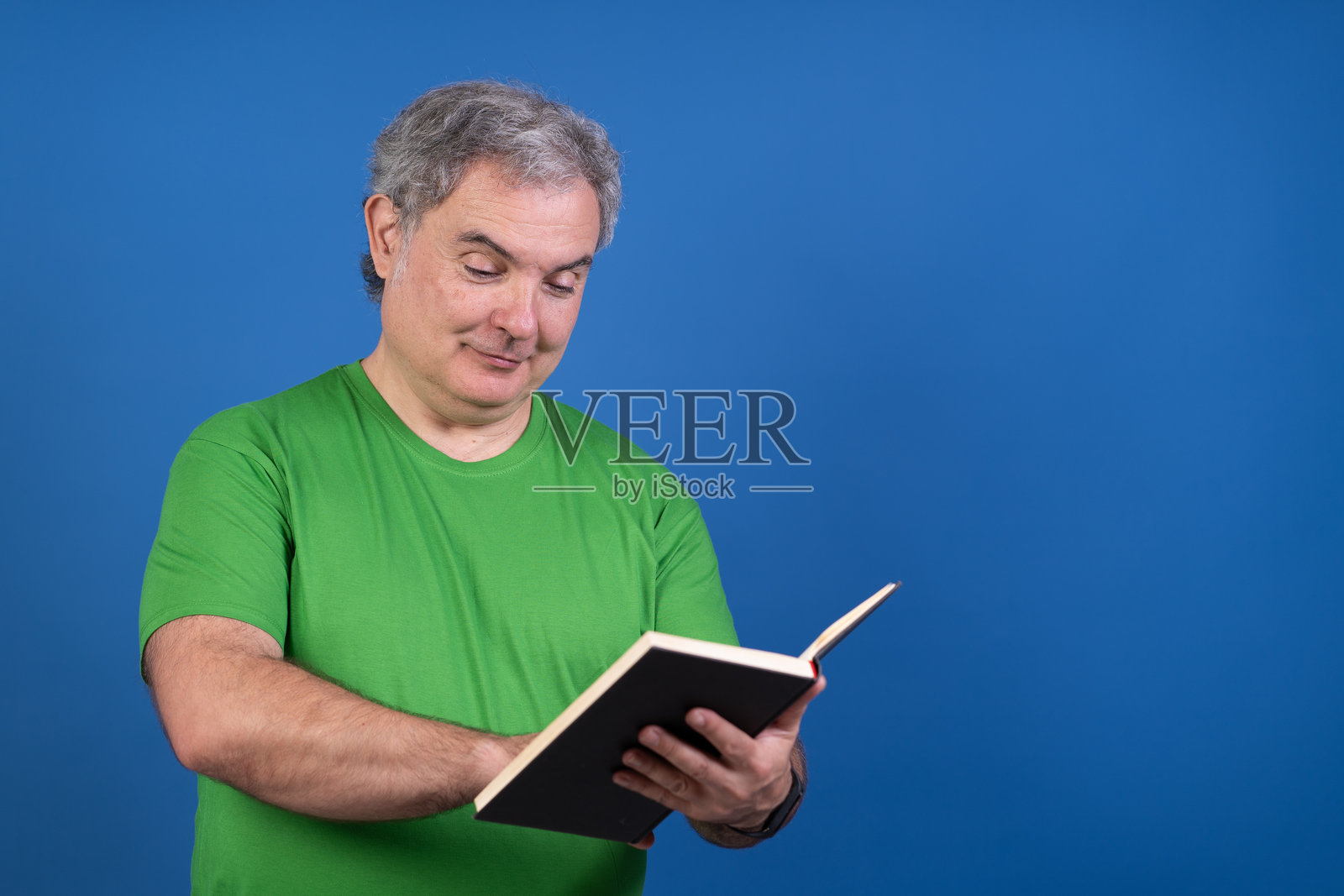 一个穿着绿色衬衫的男人正在阅读一本书照片摄影图片