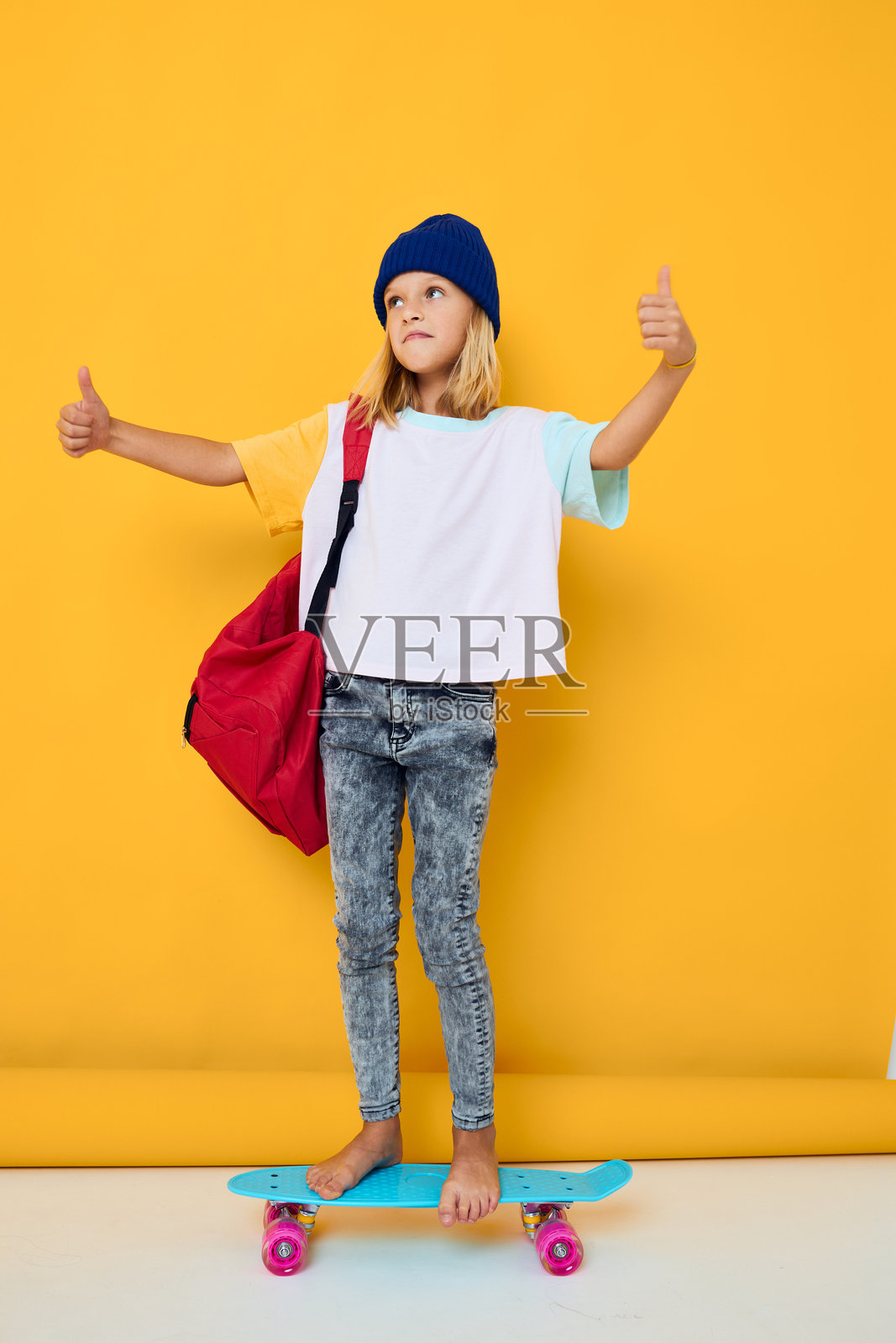 女孩骑着滑板，背着红色背包，童年生活方式概念照片摄影图片