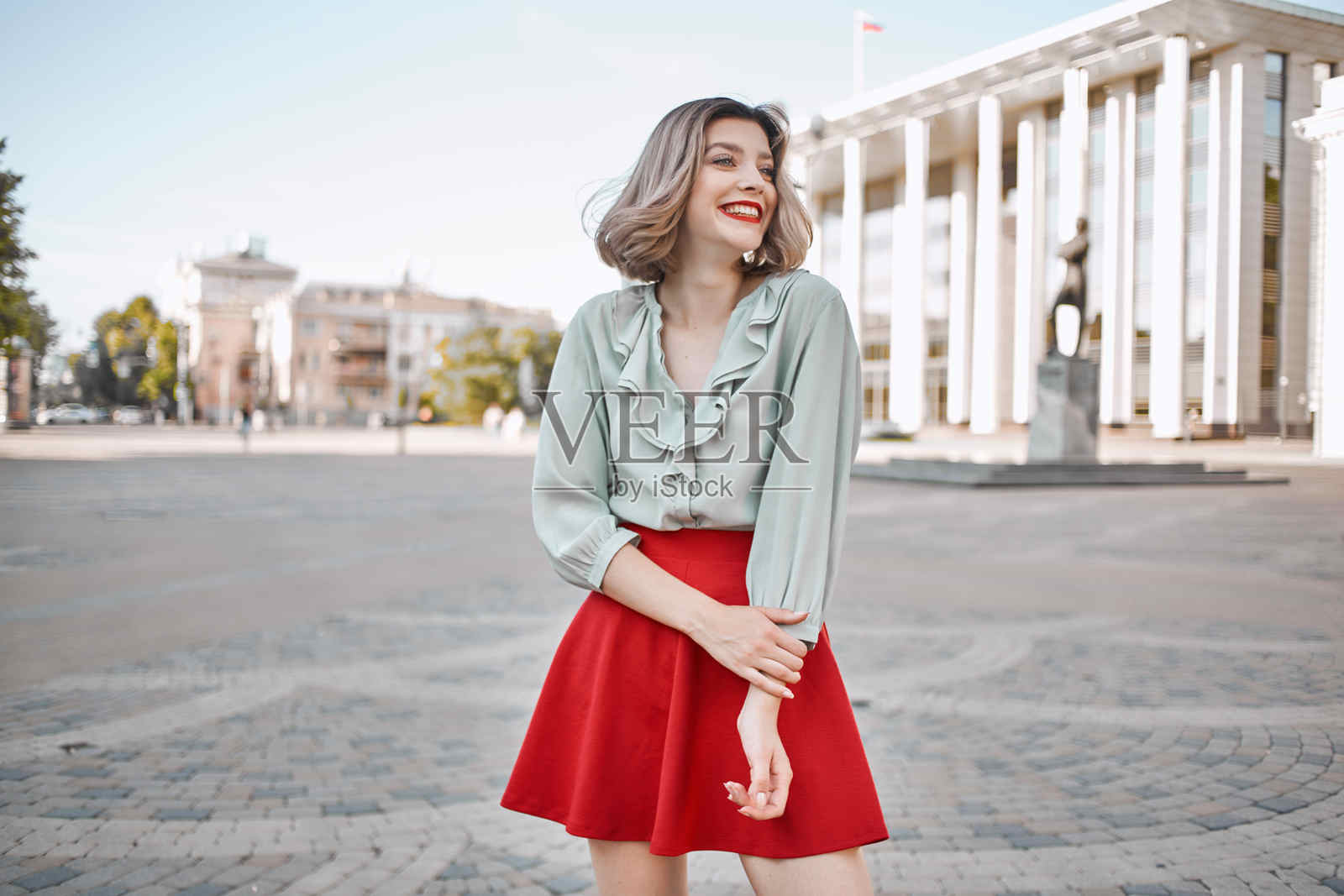 穿着红色裙子的快乐女性在户外广场摆姿势照片摄影图片