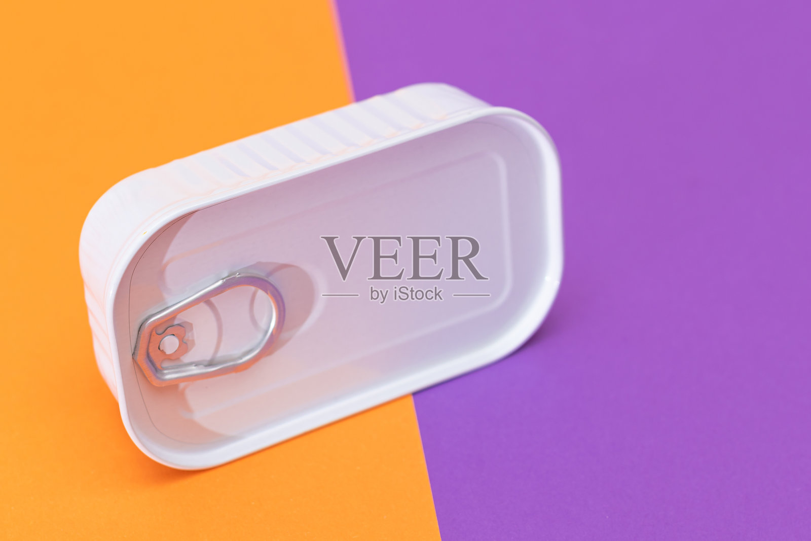 未开封的铁罐置于橙色和紫色的背景上照片摄影图片