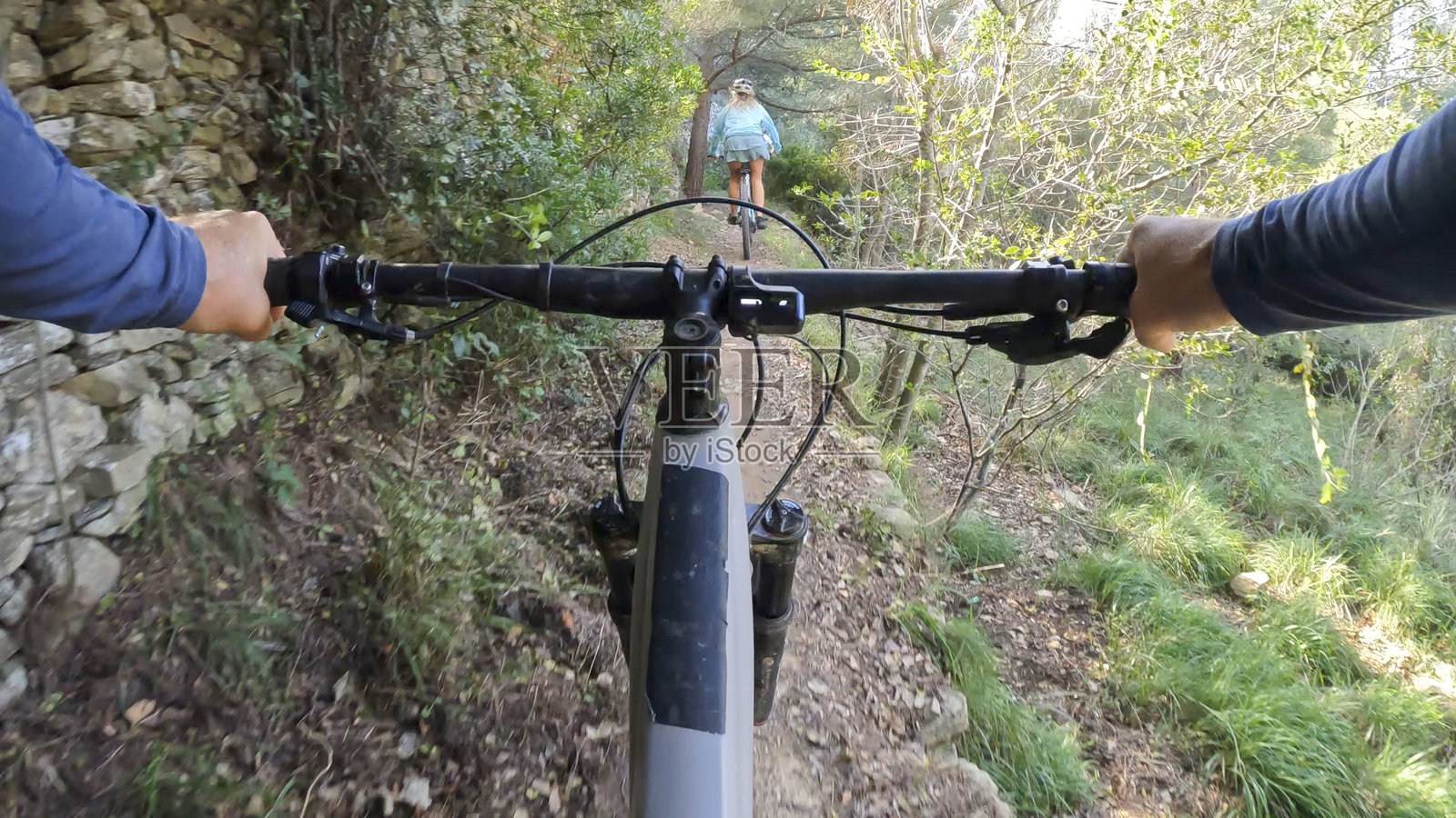 从山地自行车把手的视角看一位年轻女性在森林中骑行照片摄影图片