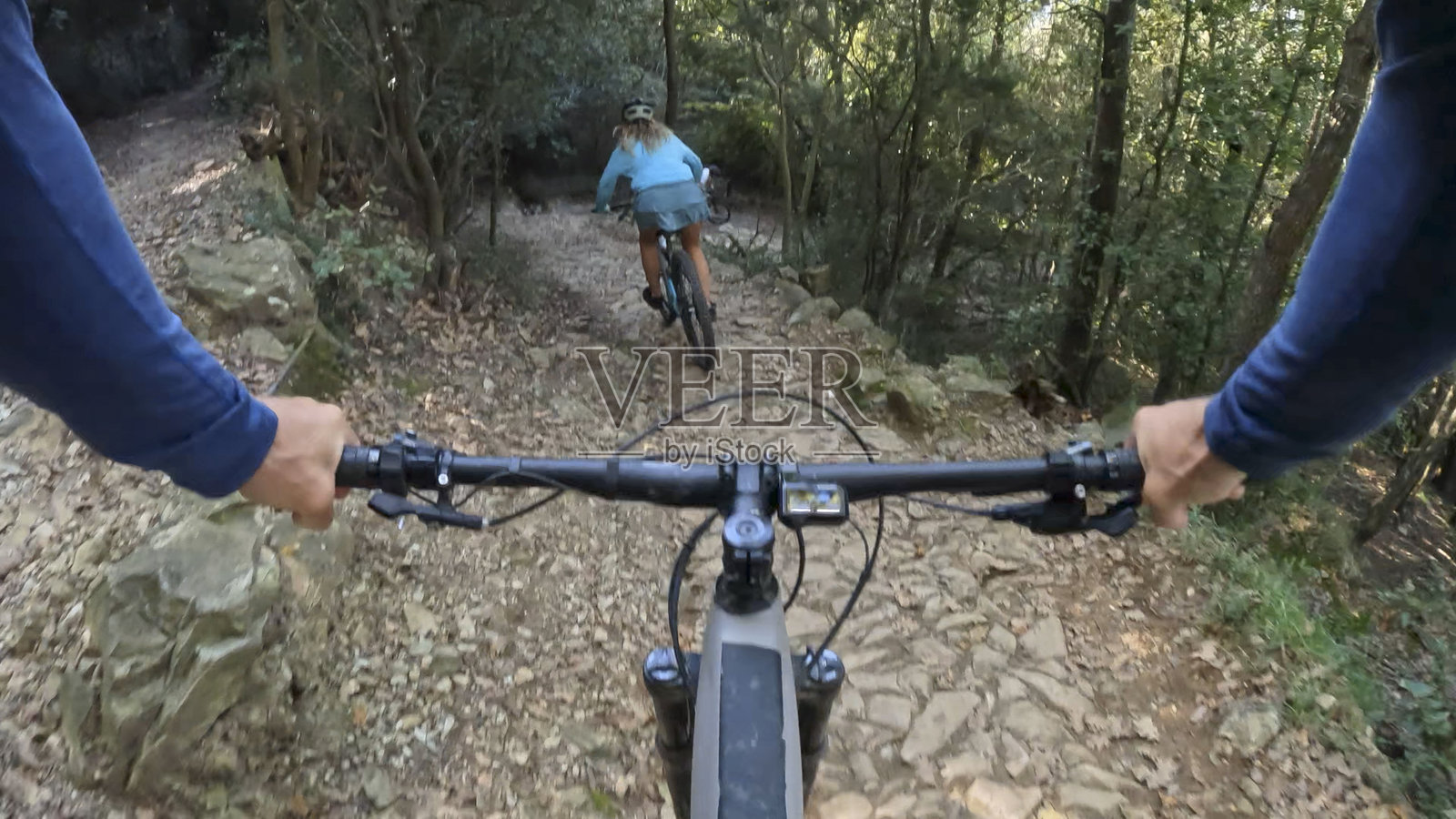 从山地自行车把手的视角看一位年轻女性在森林中骑行照片摄影图片