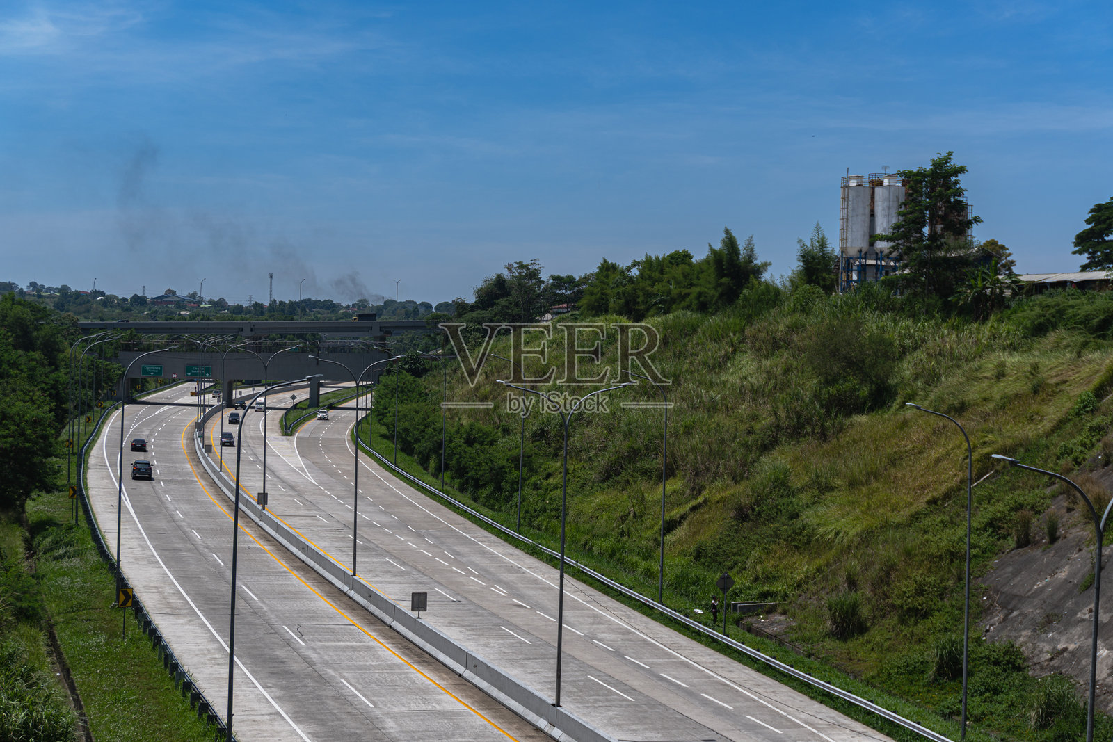 印度尼西亚博戈尔 - 2024年10月22日：高速公路蜿蜒穿过博戈尔县利多地区的绿色山坡。照片摄影图片