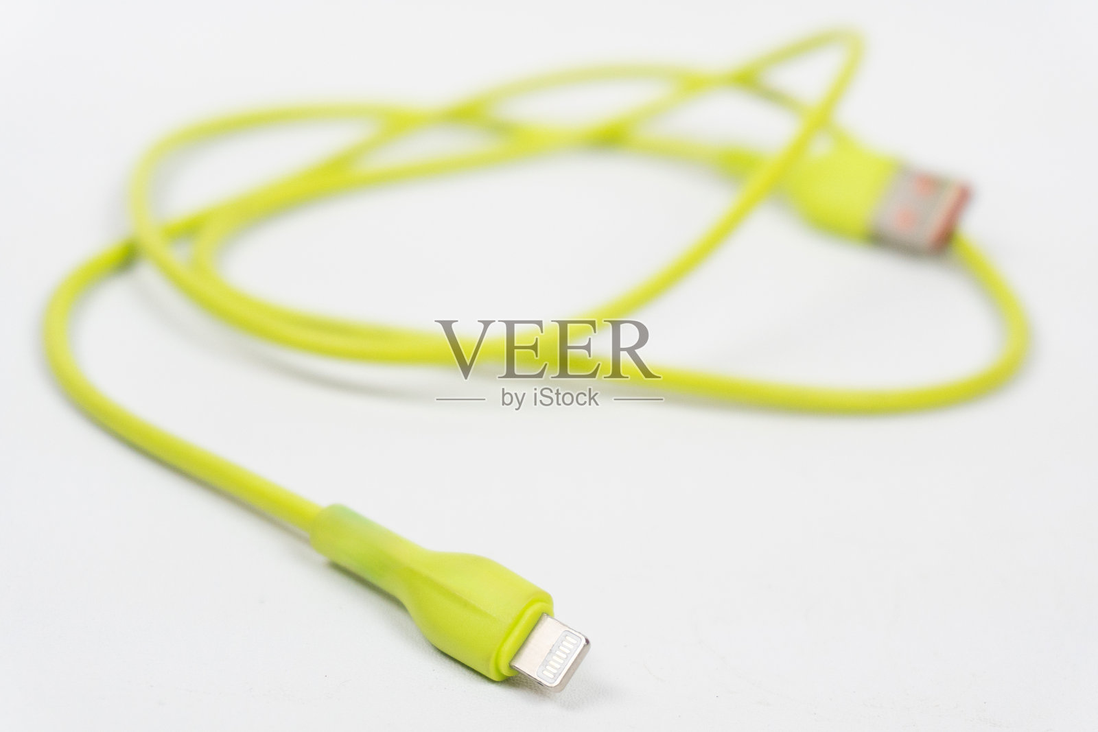 一条明亮绿色的USB充电手机数据线，背景为白色。照片摄影图片