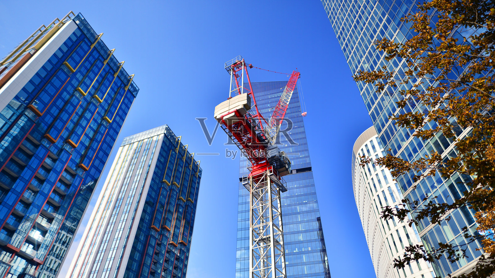 建筑工地上的起重机，周围被高楼大厦环绕。照片摄影图片