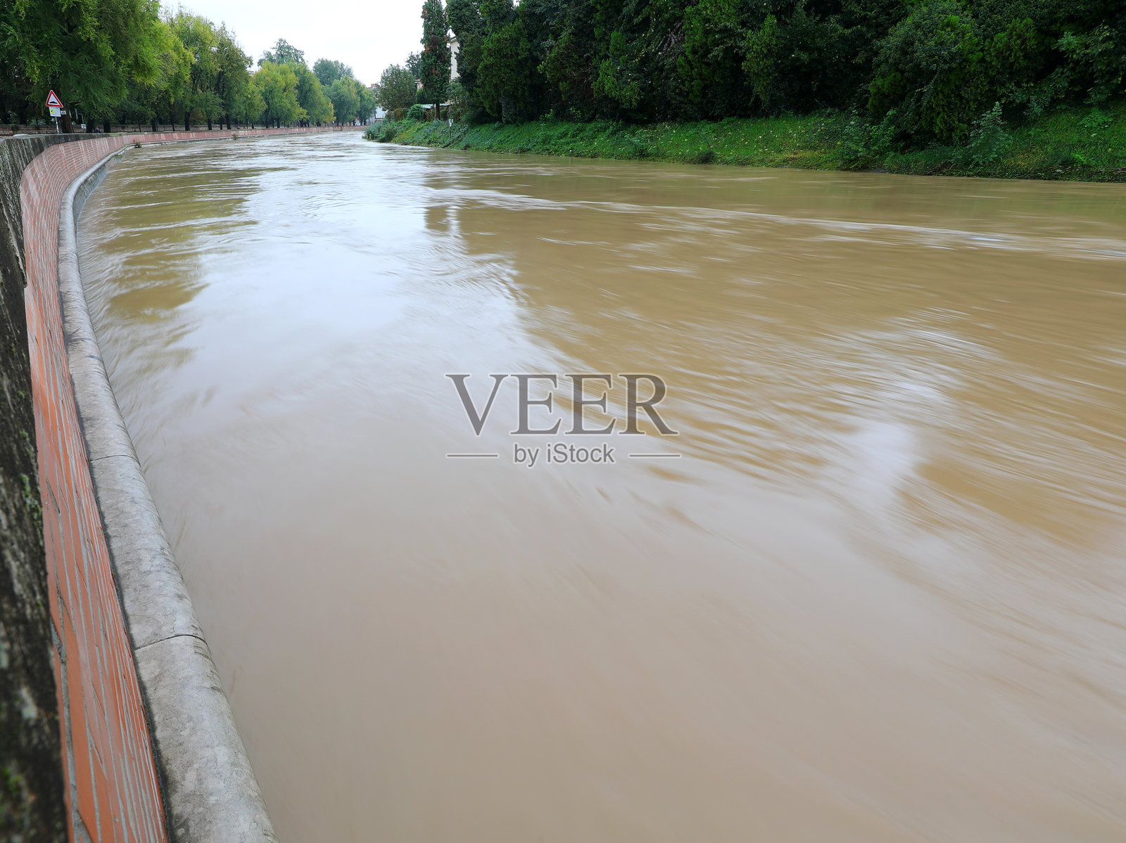 泥泞的河流弯道洪水泛滥，淹没了保护城市的堤岸照片摄影图片