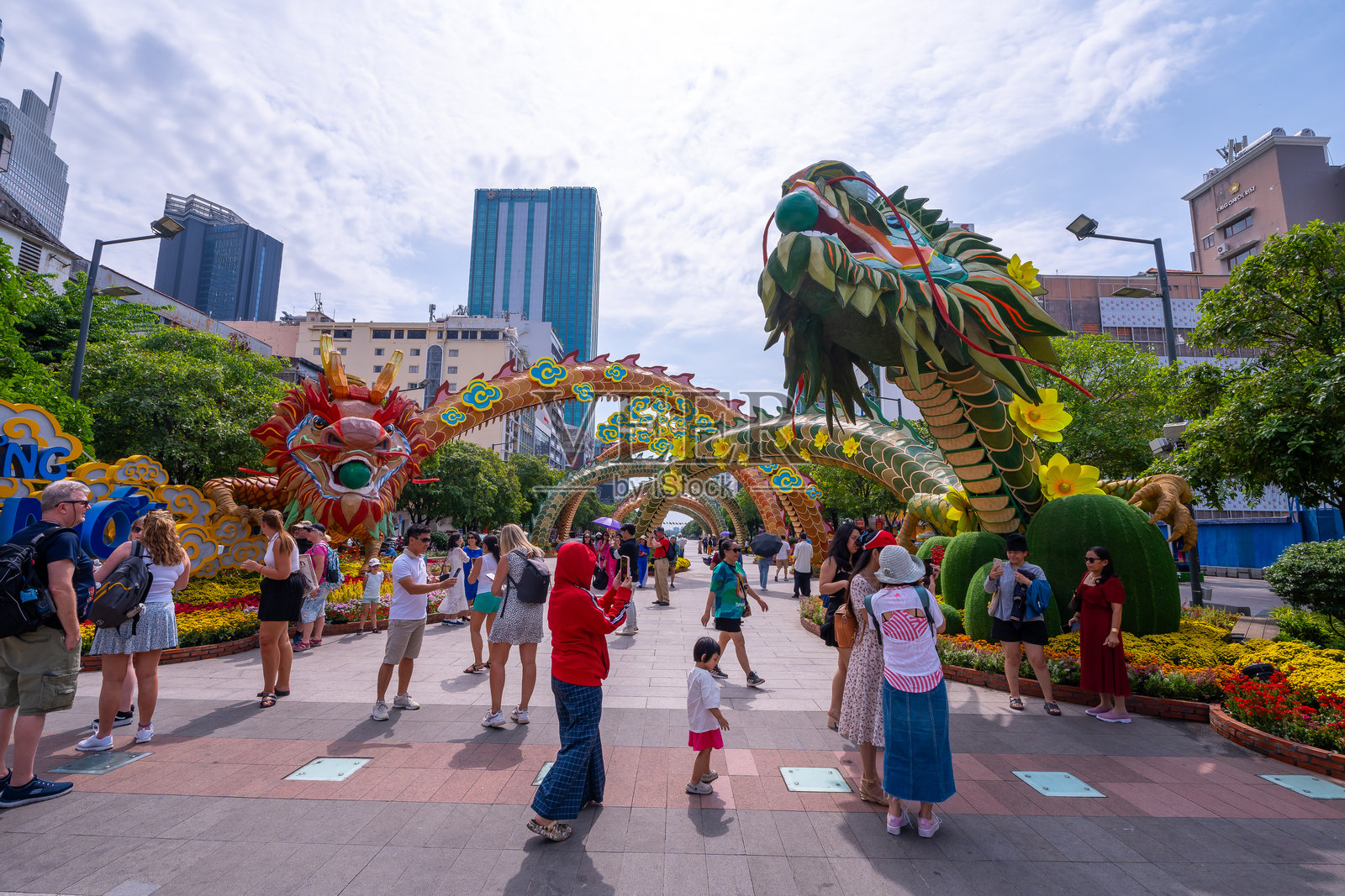 越南农历新年。人们穿着越南传统的奥黛,在街上与黄花杏和龙的装饰合影,庆祝春节。照片摄影图片