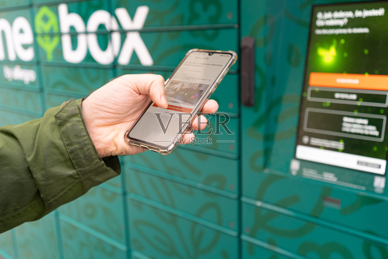 一个包裹投递箱，快递自助柜。一个人正在使用智能手机打开包裹柜，新闻报道。照片摄影图片