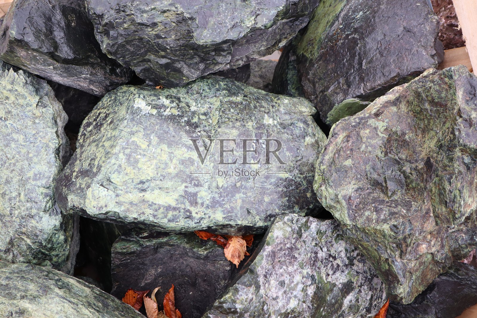 自然质感的绿色和黑色石头在风景如画的环境中美丽地排列。照片摄影图片