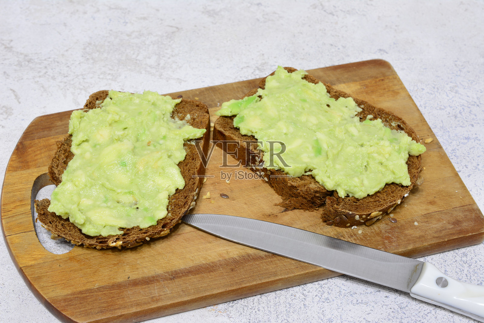 一个切菜板，上面放着鳄梨吐司和一把刀照片摄影图片