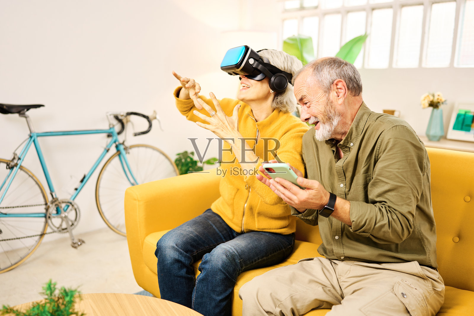 老年夫妇在家中玩虚拟现实头盔和智能手机照片摄影图片