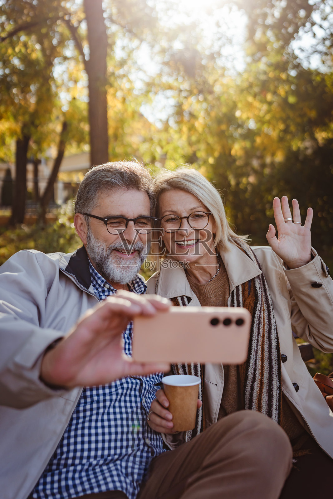一对老年夫妇在秋天的公园里自拍，微笑着享受着美丽的秋叶时光。照片摄影图片