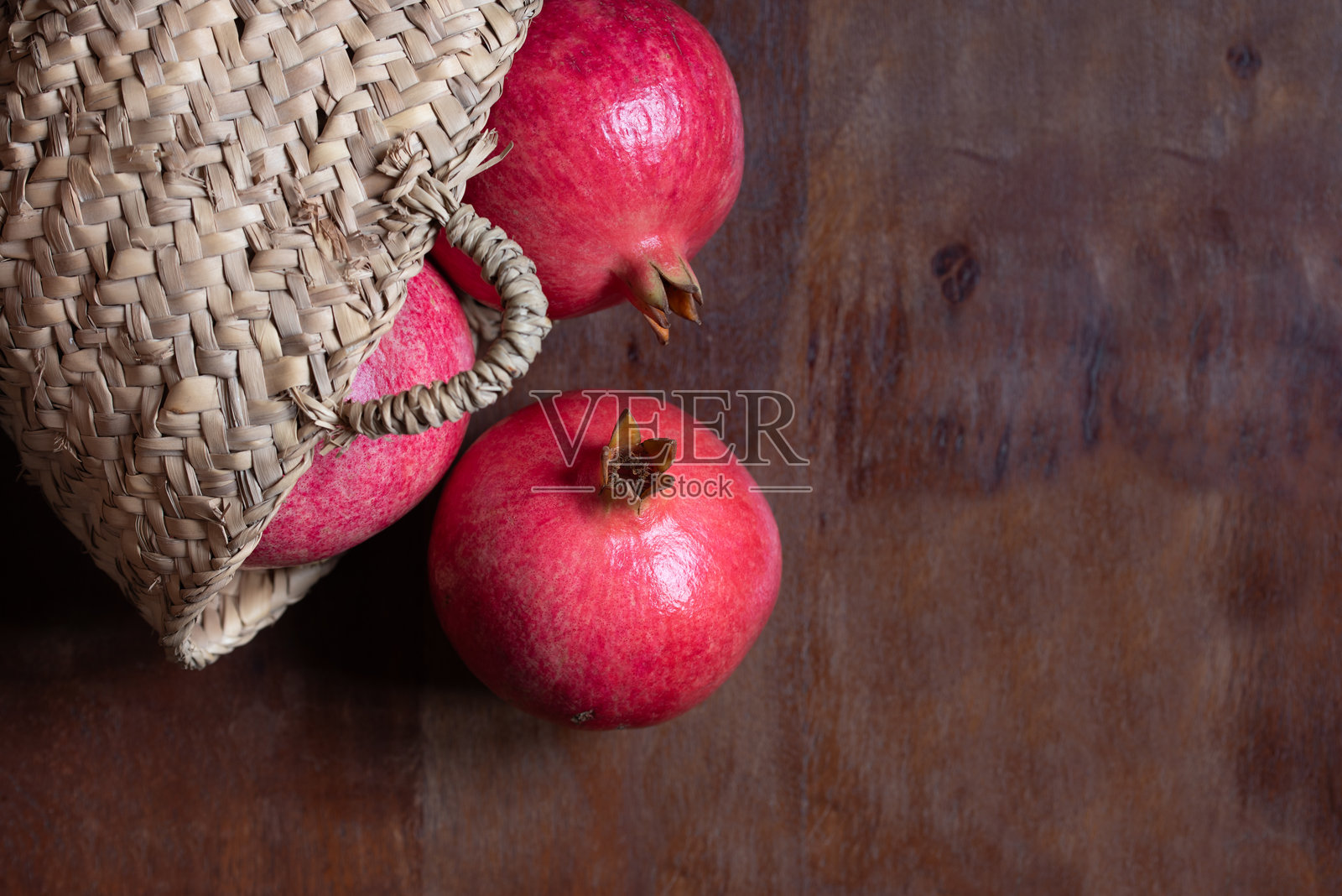 成熟的红石榴特写，放在一个乡村风格的桌子上。石榴在篮子里，从上方拍摄。照片摄影图片