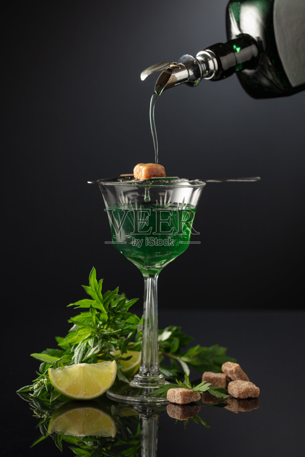 从一瓶复古的瓶子中倒入一杯苦艾酒。照片摄影图片