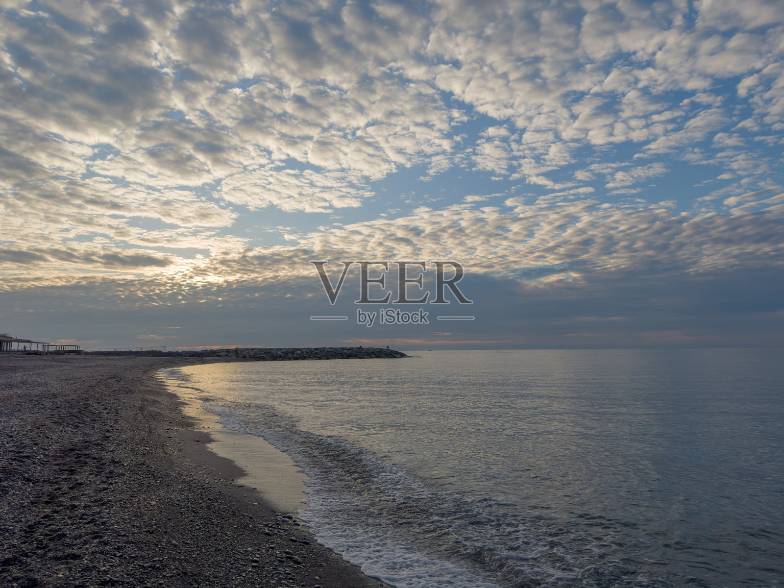 阴云密布的早晨，海边的卵石滩与天空相映成趣照片摄影图片