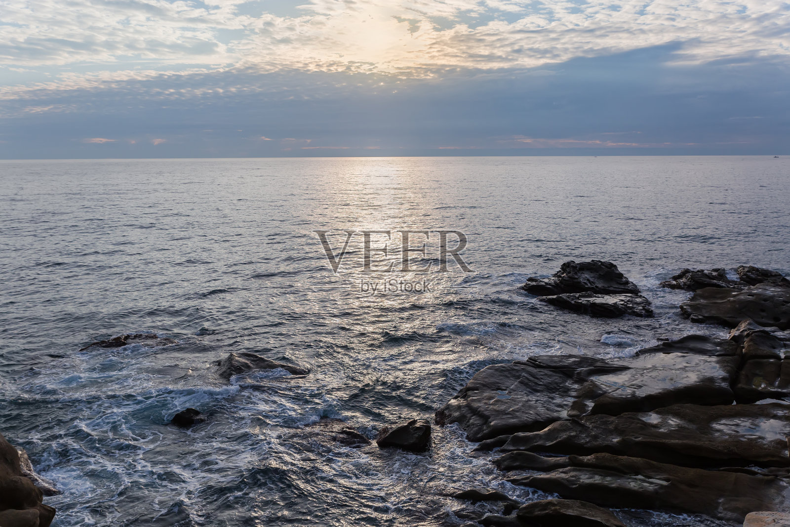 阴云密布的早晨，海边的石岸与天空相映成趣照片摄影图片