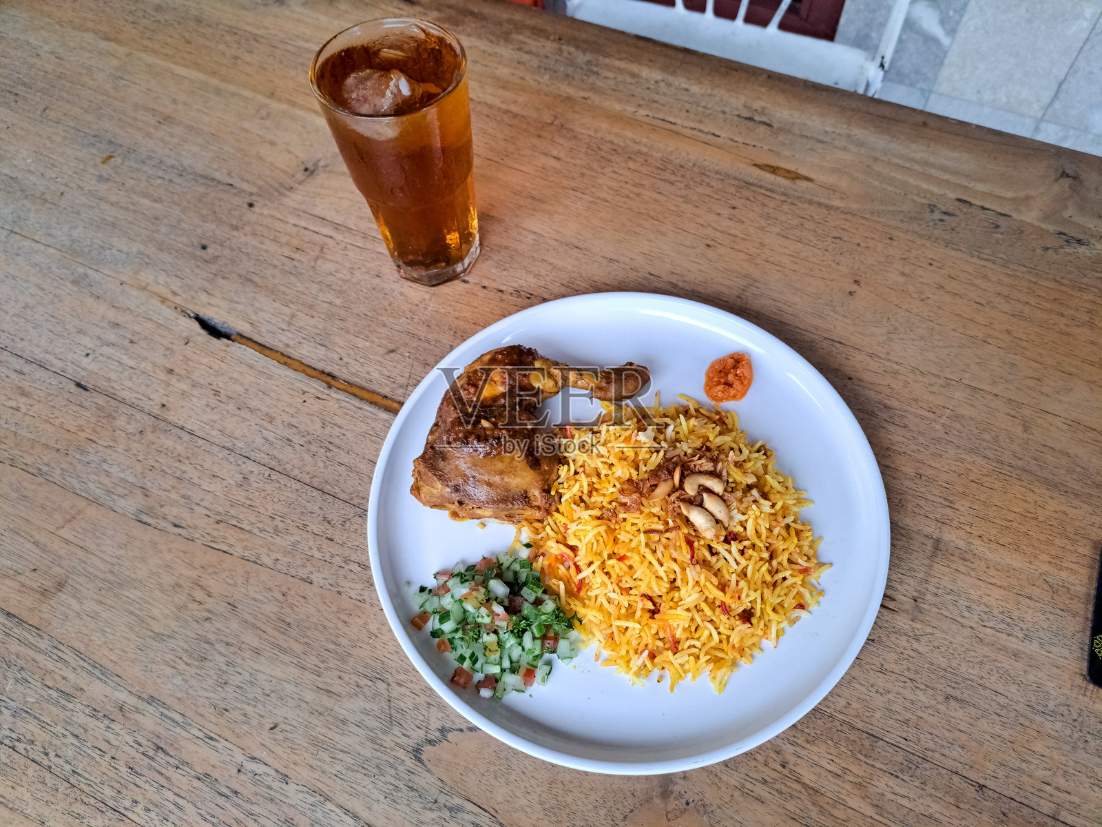 鸡肉香饭或鸡肉炒米饭，配炸洋葱、腌制品、腰果和辣椒酱。新鲜冰茶。食品和饮料菜单。照片摄影图片