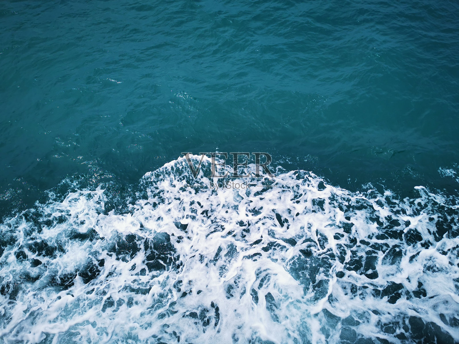 波浪的泡沫拍打着蓝色海洋中的船只照片摄影图片