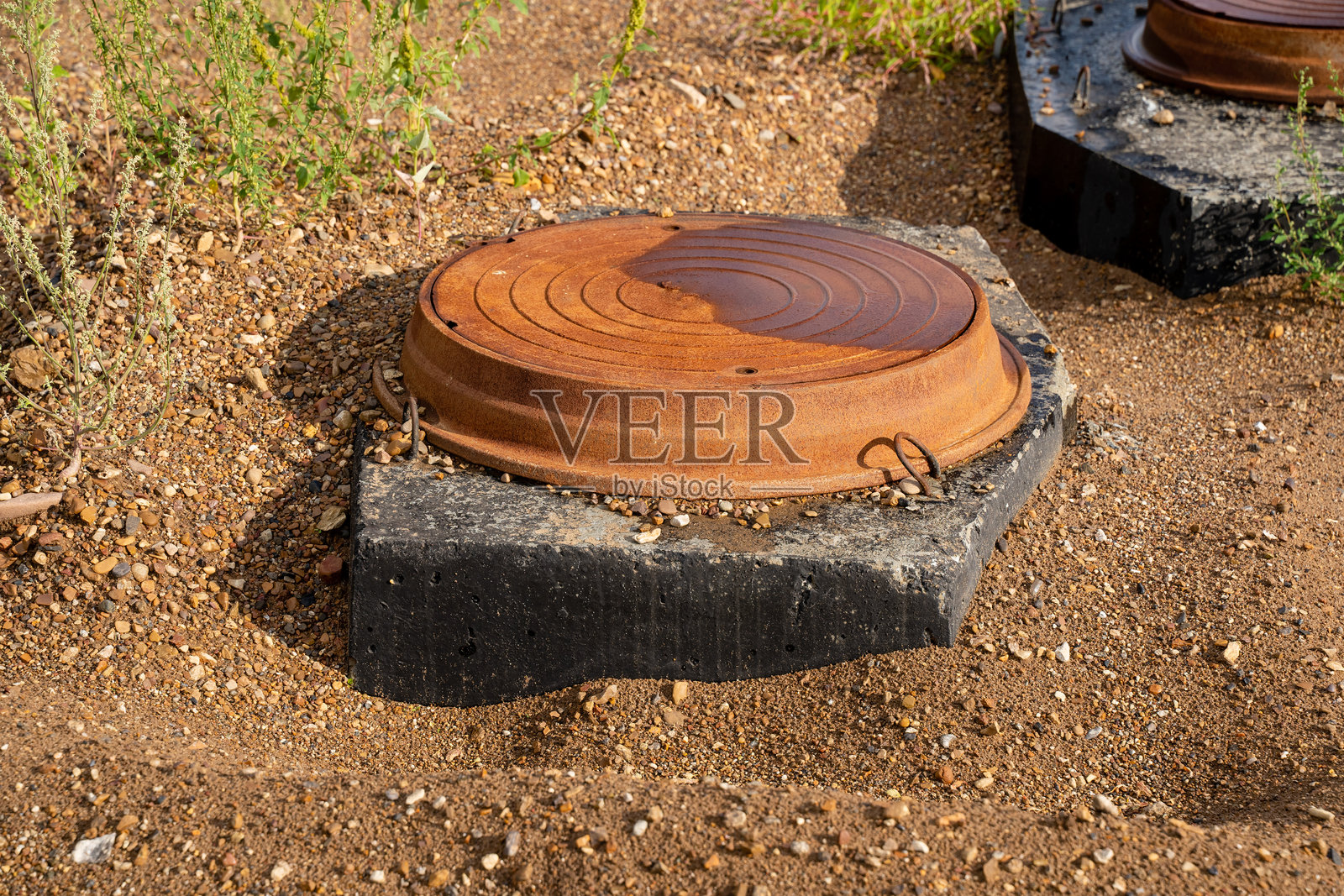 一个井盖正放在泥土中的混凝土块上照片摄影图片