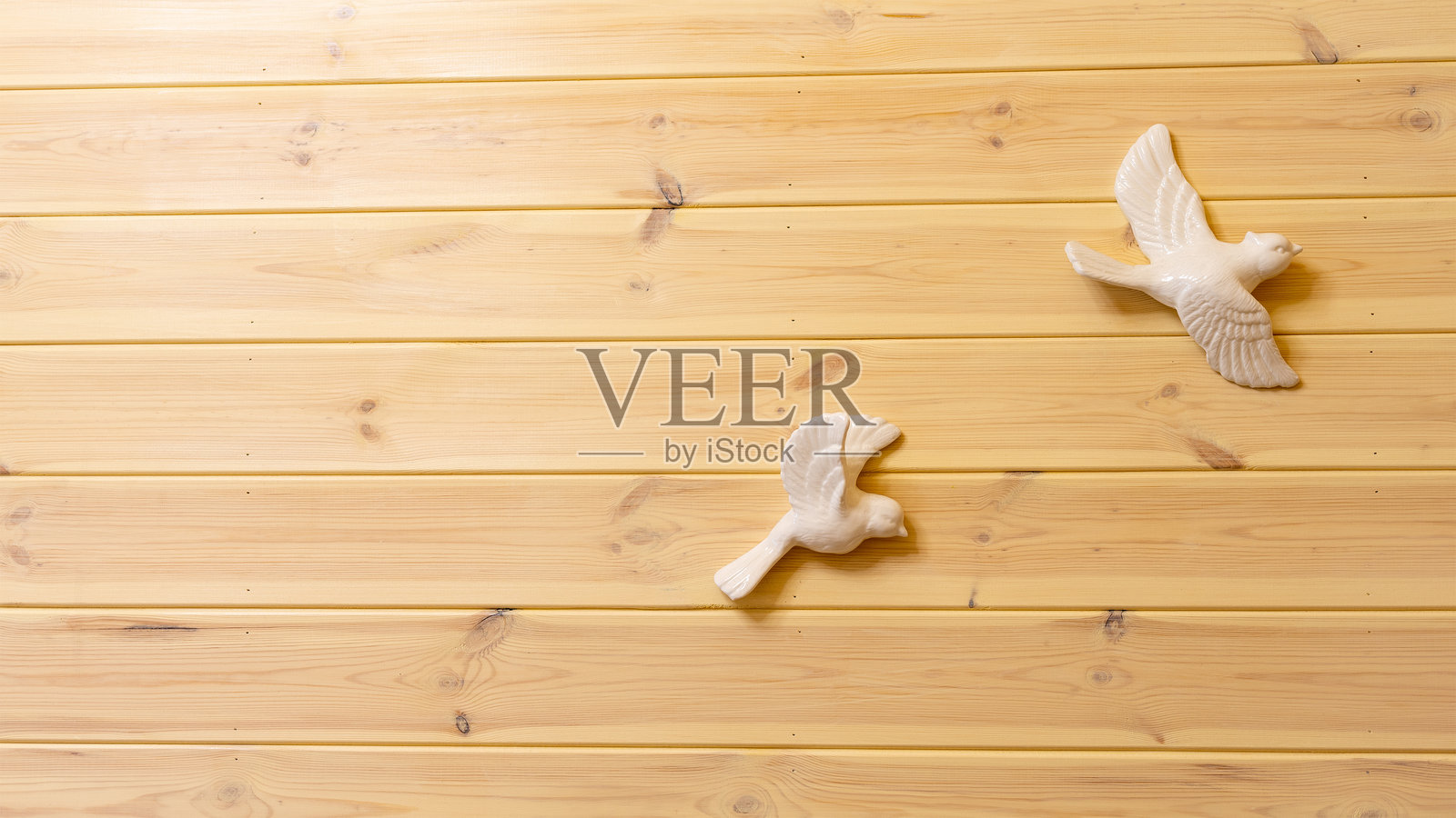 墙上装饰着陶瓷白鸟，背景为木质护墙板或木板。自然背景上的标语横幅。留白供文字使用。照片摄影图片