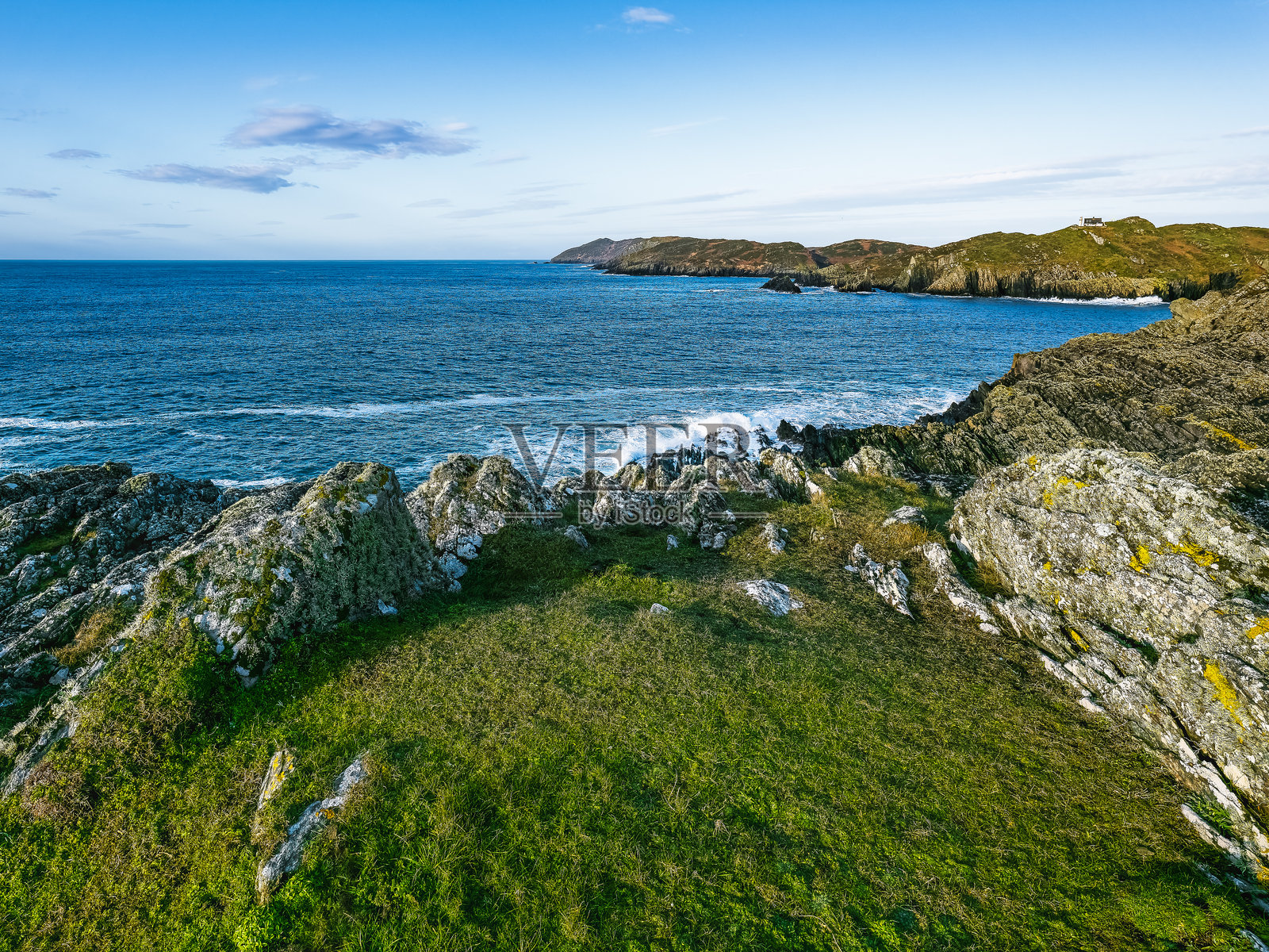宁静的海岸线展现了崎岖的悬崖和起伏的海浪，前景中绿意盎然，捕捉了阳光明媚的日子里大自然的美丽。照片摄影图片