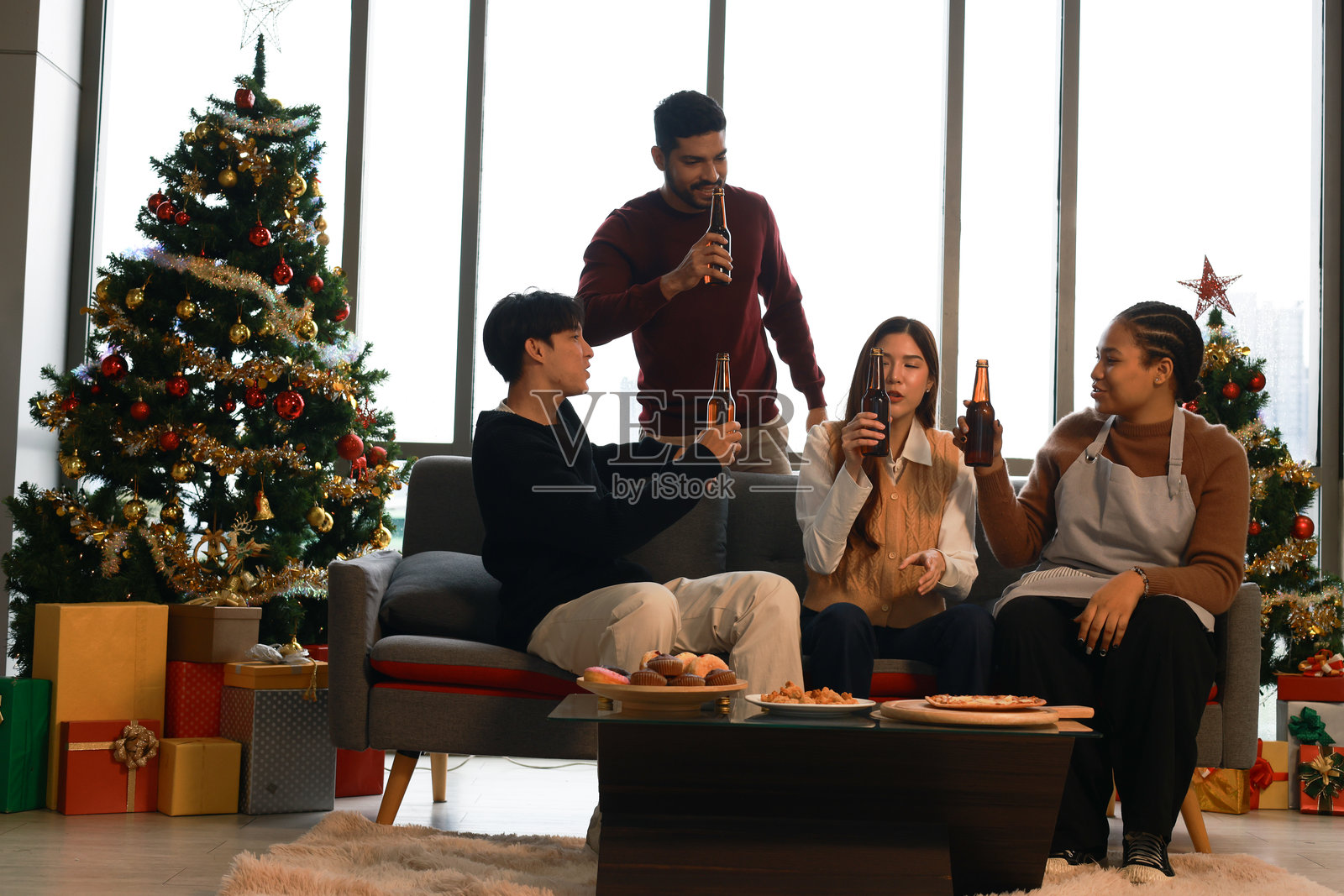 一群多元化的朋友在家庆祝圣诞节，手中举着酒杯。庆祝气氛热烈，手中有香槟瓶、葡萄酒和鸡尾酒。照片摄影图片