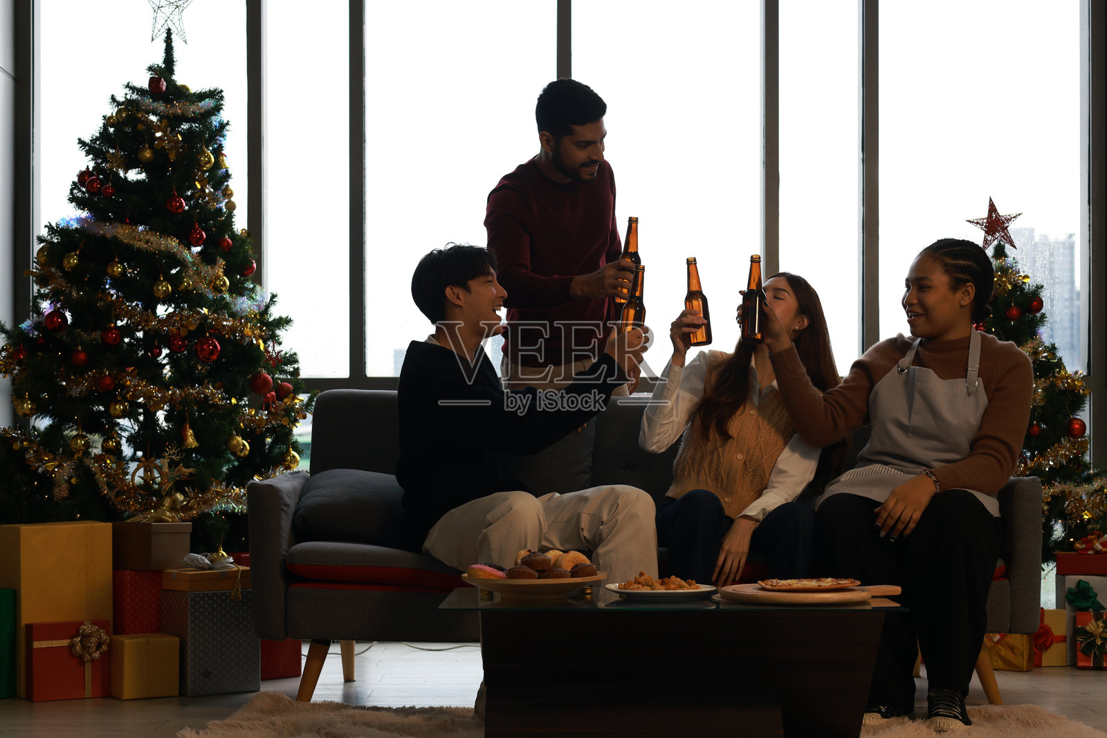 一群多元化的朋友在家庆祝圣诞节，手中举着酒杯。庆祝气氛热烈，手中有香槟瓶、葡萄酒和鸡尾酒。照片摄影图片