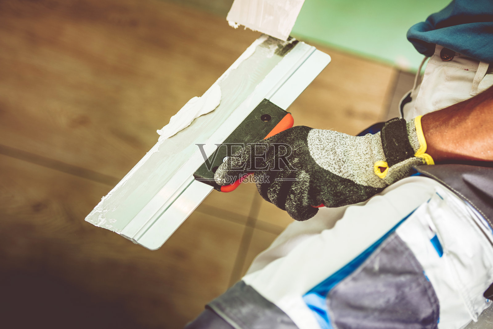 工人在明亮的室内空间用抹子涂抹墙壁。照片摄影图片