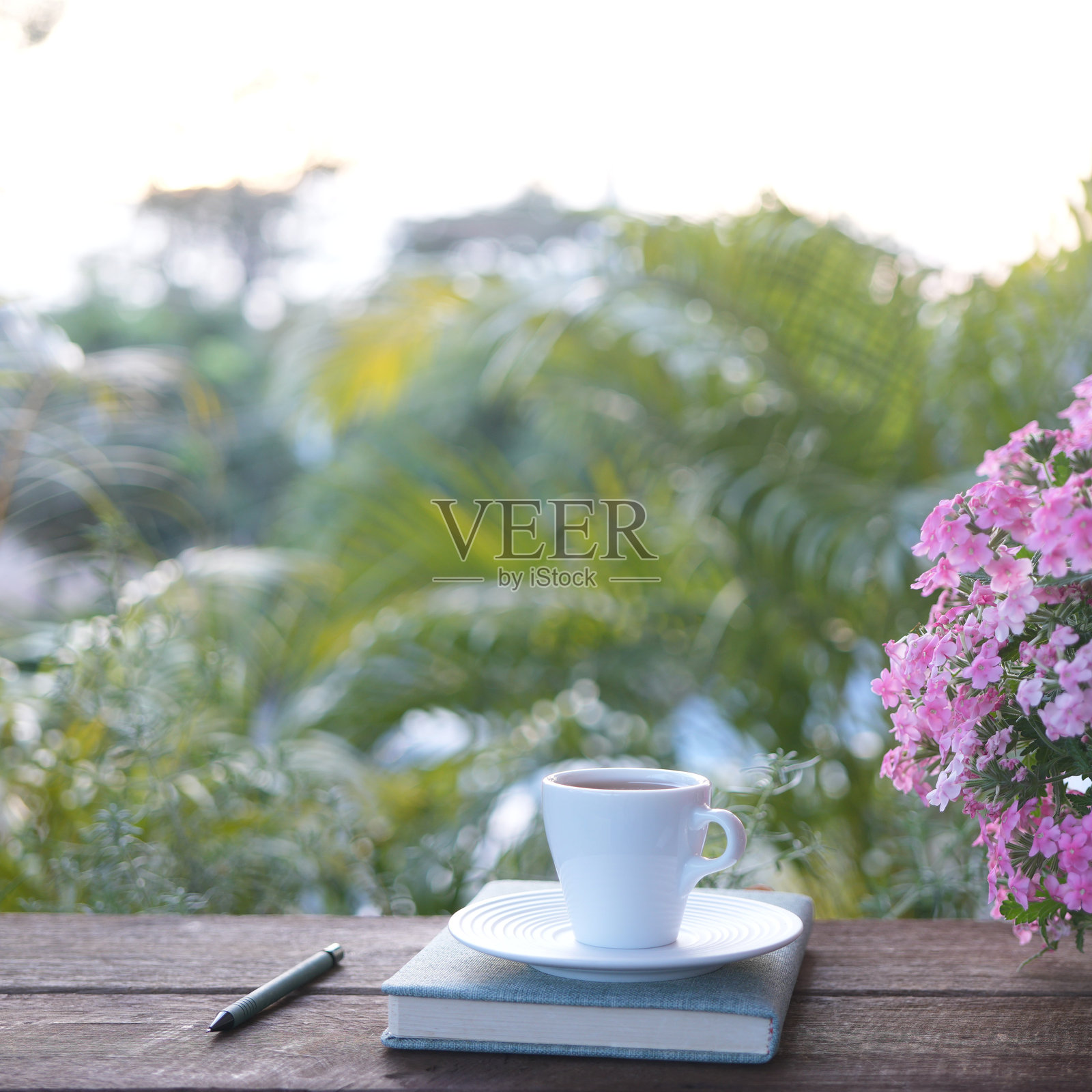 一只白色茶杯，旁边有香蜂草花和笔记本，户外工作中照片摄影图片