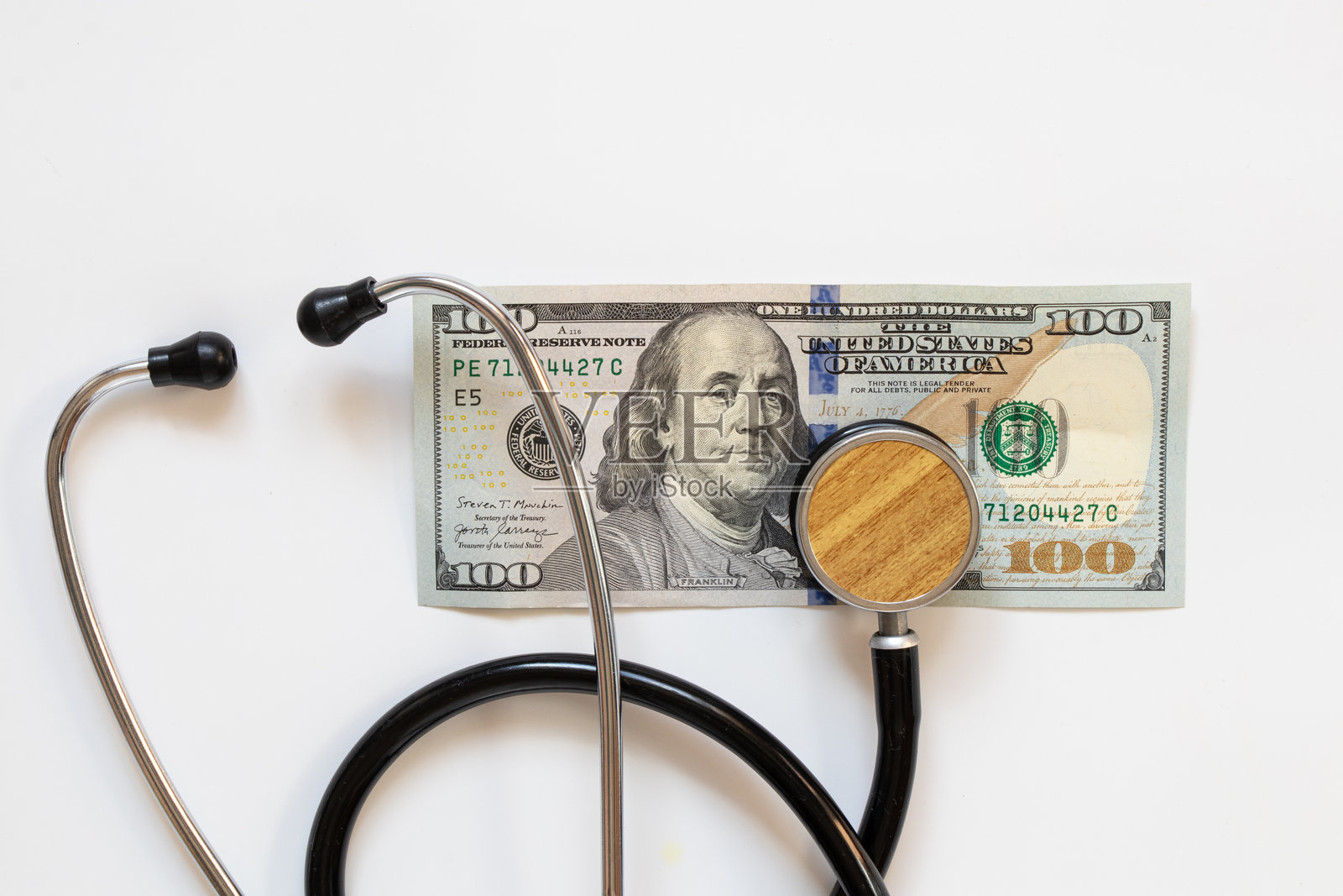 医生的听诊器和一百美元钞票放在白色背景上，金融与治疗照片摄影图片