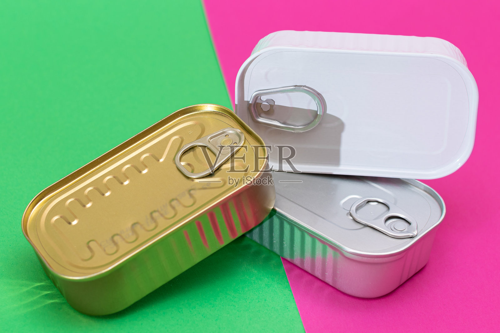 一组叠放的锡罐置于分割的绿色和青色背景上照片摄影图片