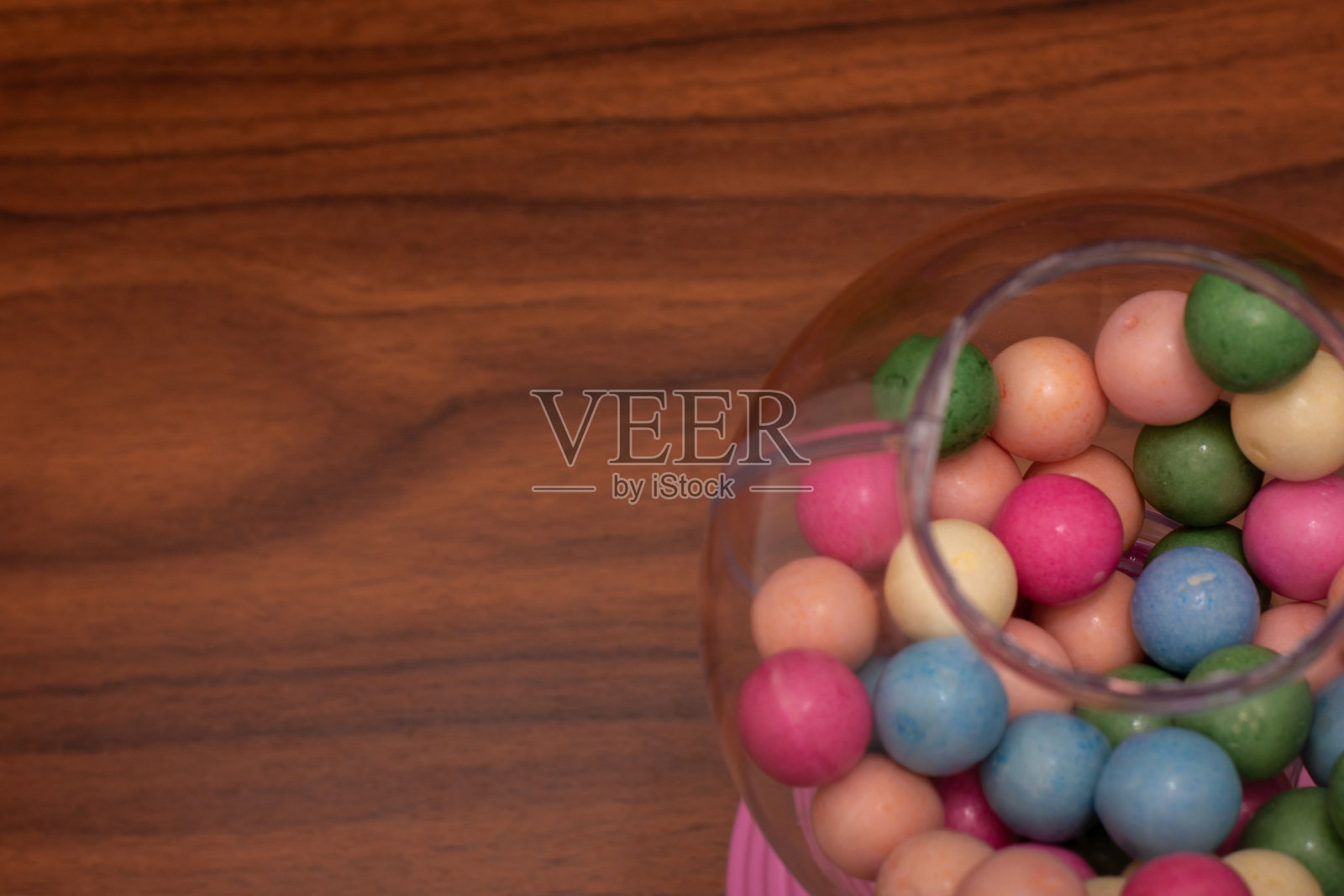 粉色的泡泡糖机，透明玻璃容器里装满了五颜六色的泡泡糖照片摄影图片