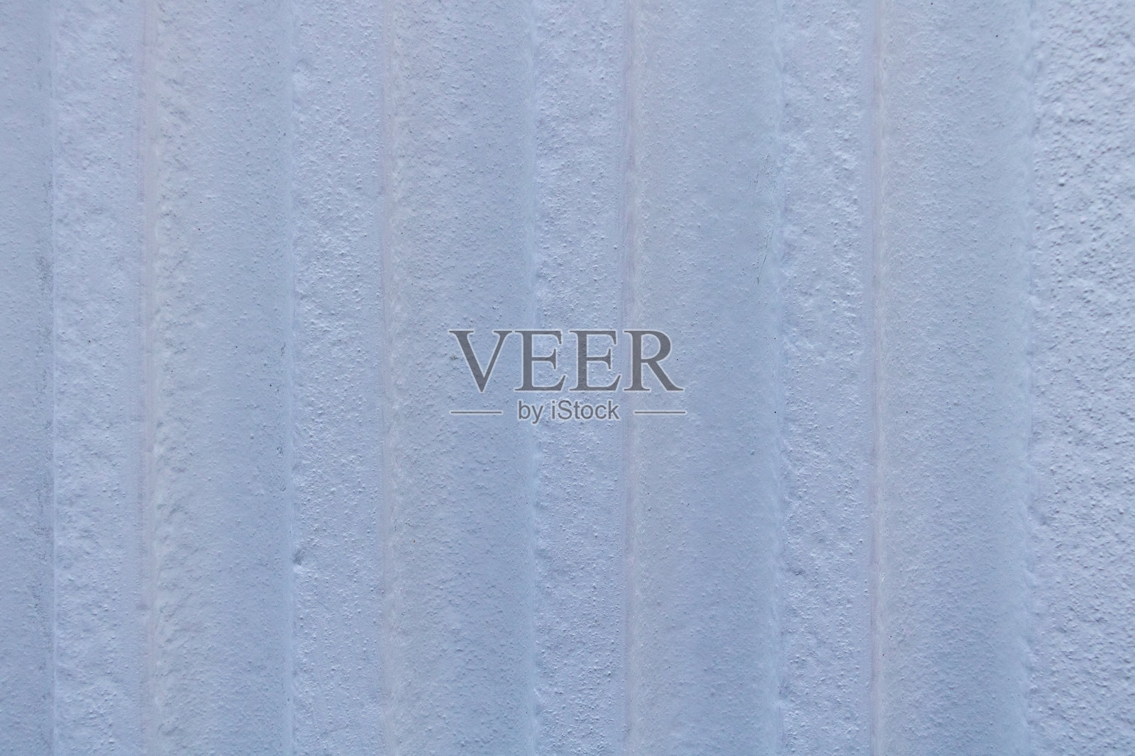 一面垂直的白色墙壁，上面有蓝色油漆的垂直线条，形成一种抽象图案，类似于混凝土或灰泥墙的质感和外观。照片摄影图片