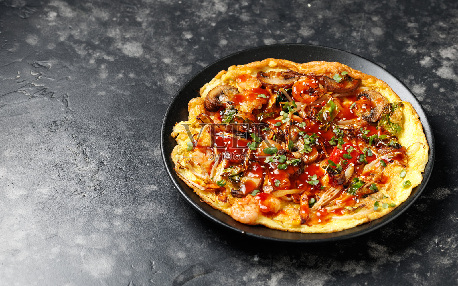 富有年轻气息的中式蛋饼，内含蔬菜、蘑菇、虾仁和酱汁照片摄影图片